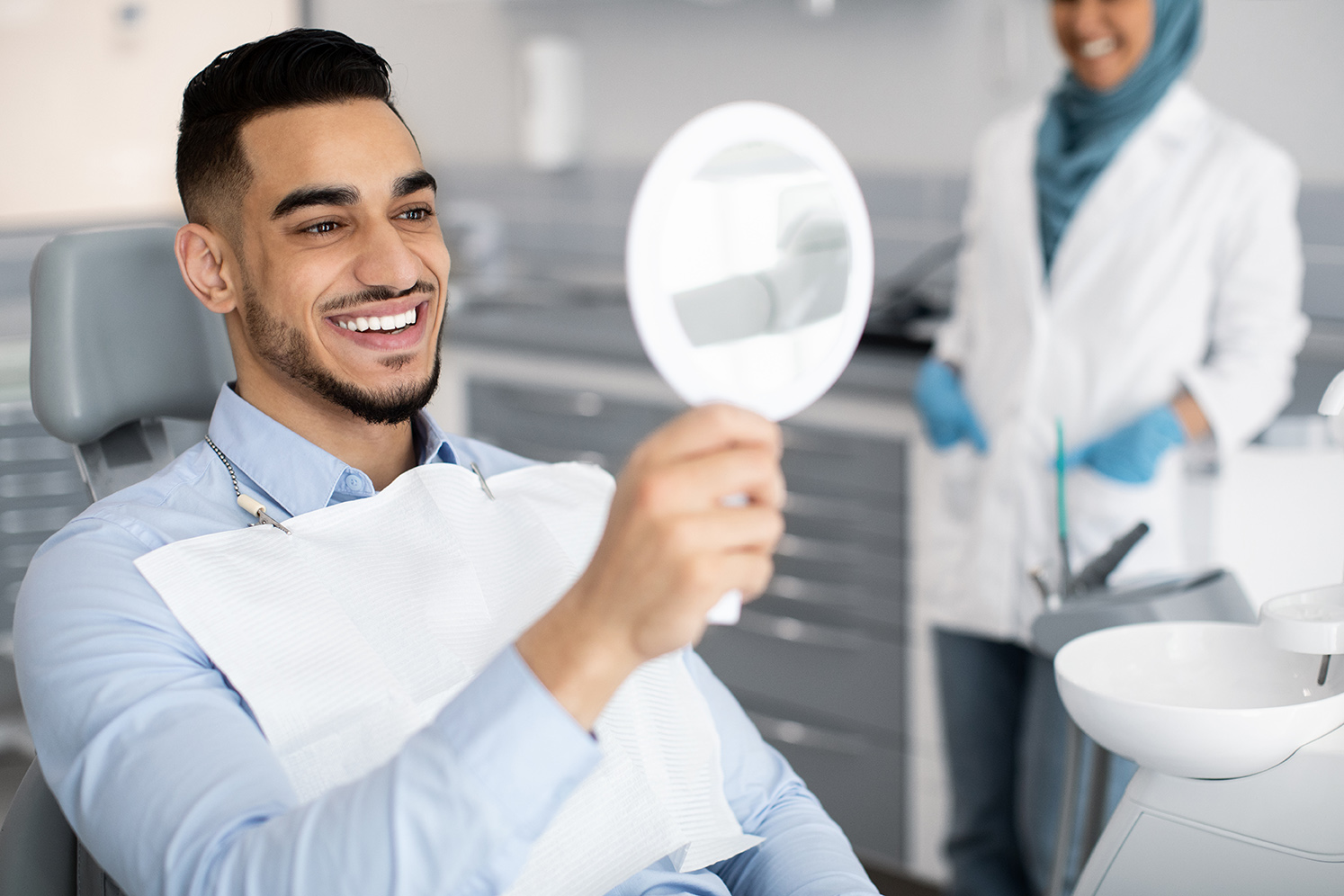 man smiling in a mirror during cosmetic dental consultation at jensen family dental in bayport mn